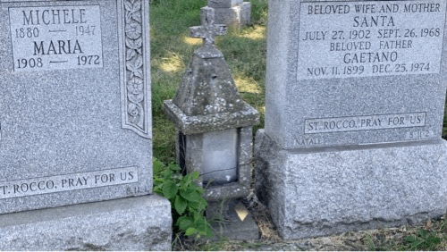 A stone lantern with glass windows and an unlit candle. The tree shading the lantern was being blown by the wind, causing sunlight to reflect inside the lantern as if the candle were lit with flame.